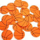 Orange basketball designed cardstock confetti pieces with black curved lines, scattered on a plain white background.