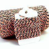 Thin crafting twine in a black, orange, and white pattern, wrapped around a white hang tag.