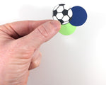 Hand showing size of 1 inch soccer and colored circle confetti